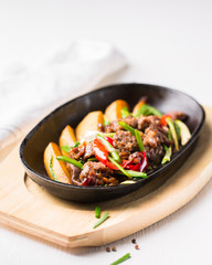 Grilled steak, baked potatoes and vegetables.  Beef meat stewed with potatoes, carrots, sweet red peppers, green onions and spices in frying pan on white wooden table.