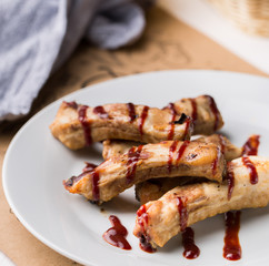 Gourmet main dish with grilled pork rib on white plate. Served on wooden table. Flat lay, top view.