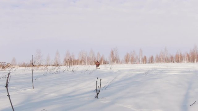 Man in winter clothes fast riding and maneuvering on mini snowmobile on deep snowdrifts