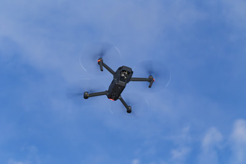 Unmanned aerial vehical with video camera hovers in the air. This is DJI Mavic Pro model.