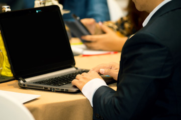 Hands of people wear black suit using laptop on the table while conference meeting in the hotel.