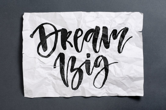 Dream big. Handwritten text on white crumpled paper. Inspirational quote.