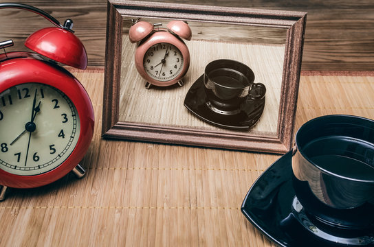 Red alarm clock and cup of black coffee on office desk table background. Coffee break concept.