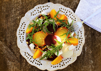 Healthy Beet Salad with red, white, golden beets, arugula, nuts, feta cheese on wooden background