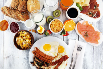 Traditional full English breakfast with fried eggs, sausages, beans, mushroomsand bacon on wooden background
