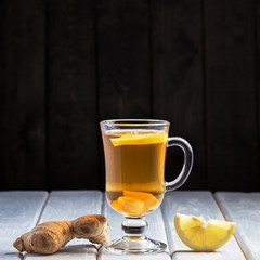 A cup of ginger tea with lemon on a wooden background.