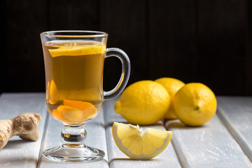 A cup of ginger tea with lemon on a wooden background.