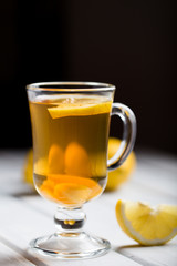 A cup of ginger tea with lemon on a wooden background.