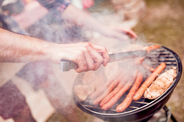 Handsome happy male preparing barbecue outdoors.