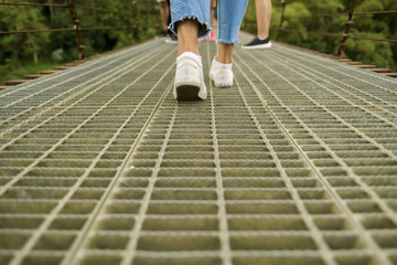 Woman jeans and sneaker shoes walking on the bridge with outdoor nature and blur leg people