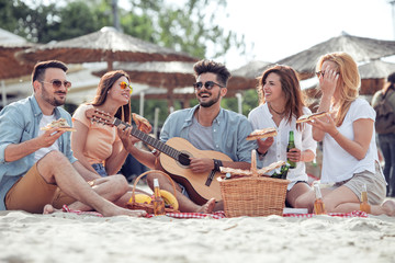 Happy people eating pizza and have fun on the beach.