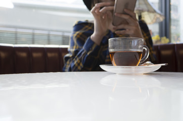 スマートフォンを使う女性が頼んだ紅茶。