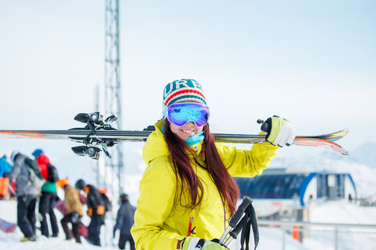 Image of smiling sports woman with skis on her shoulder