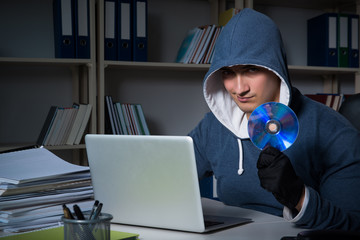Young hacker hacking into computer at night