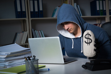 Young hacker hacking into computer at night