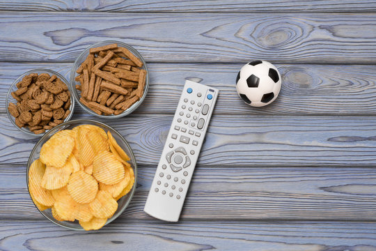 chips, crackers, TV remote, ball. football fans. football.