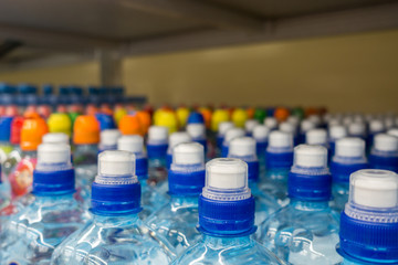 Plastic bottles with mineral water. Closeup on  water bottles in raw and lines. Plastic bottles, colorful caps. Plastic bottles with water, lids.