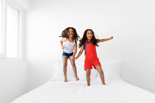 Happy little girls wildly jumping on bed