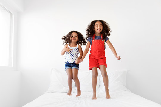 Little girls jumping on bed with big smile