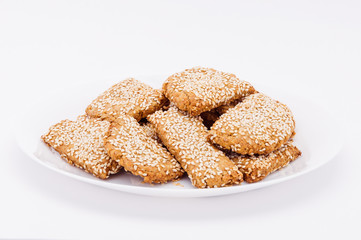 Fototapeta na wymiar On a white plate, on a white background fresh biscuits to sesame.