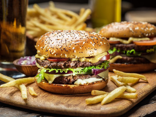 Hamburgers and French fries on the wooden tray.