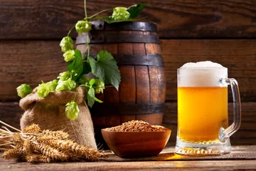 Foto auf Leinwand Krug Bier mit grünem Hopfen, Weizenähren und Holzfass © Nitr
