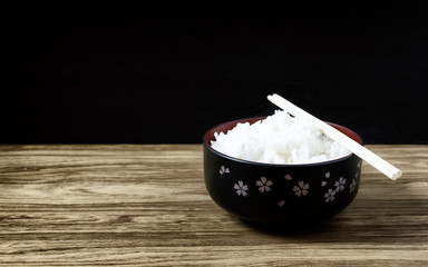 Rice hot chopsticks in a bowl of black on wooden floor
