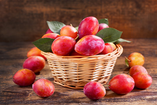 fresh plums with leaves in a basket
