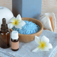 Spa blue sea salt,  relax essential oil,aromatic candle,  towel with exotic flower frangipani and shell  on wooden background with copy space. .The Health and Wellness Spa concept.