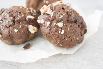 Three chocolate cupcakes with nuts on baking paper isolated