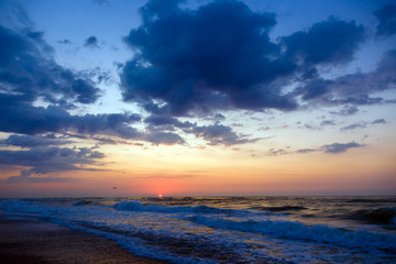 Fototapeta na wymiar Sunset on a beach. Stormy sea, cloudy sky.