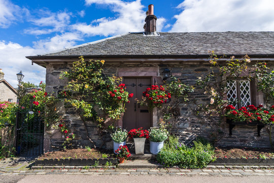 A picturesque stone cottage with red roses in the village of Luss on the banks of Loch Lomond, Scotland, Britain