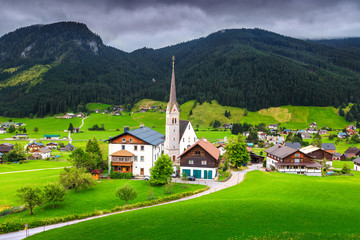 Fototapeta na wymiar Spring alpine landscape with traditional houses and green fields, Austria