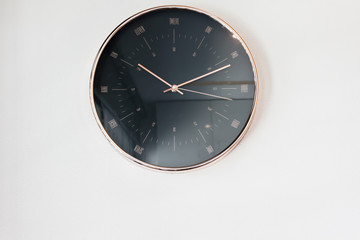 Modern black clock hanging on plain wall