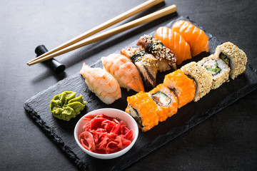 Sushi and sushi roll set on black stone table.