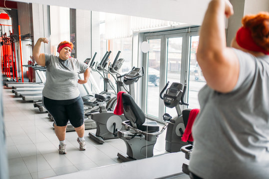 Fat sweaty woman training against mirror in gym