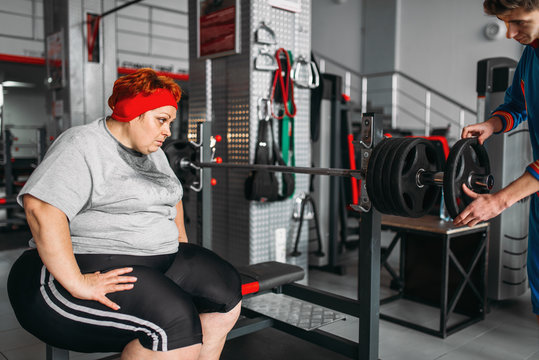 Overweight sweaty woman on workout with barbell