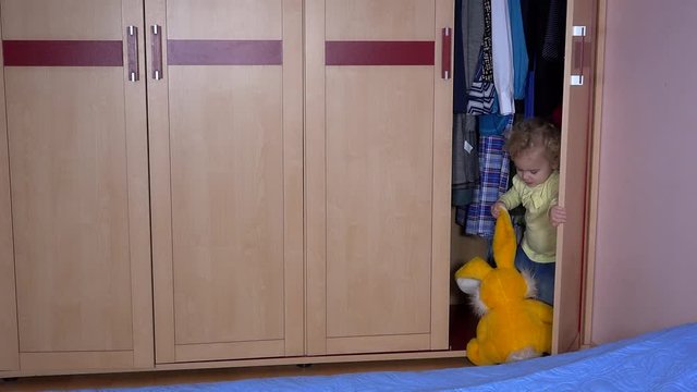 caucasian child with bunny plush friend hide in closet and close door