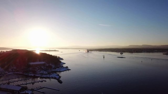 Aerial shot of islands in Oslo fjord towards sun at sunset in winter