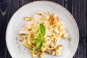 Delicious creamy italian pasta with mushrooms, parmesan cheese, basil and creamy sauce with pepper seasoning in white plate, close up. Flat lay, top view
