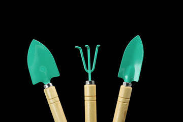 three gardening tools, rake and scoop isolated on black background