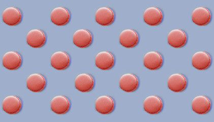 Pink macaroons scattered in different direction on blue background, flat lay