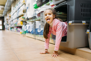 Little girl chooses carrier for puppy in pet shop