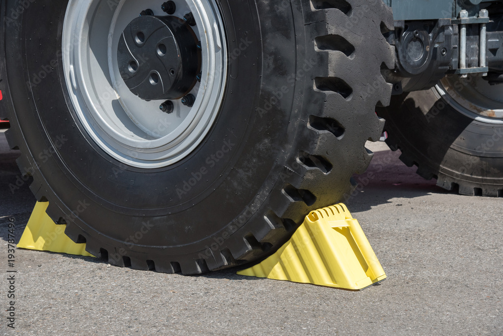 Wall mural yellow wheel chocks under the big truck wheels