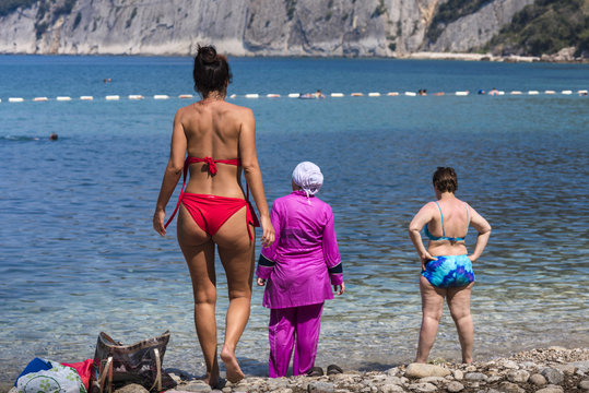 Diversity on the beach - Rear view of young and mid aged women wearing bikini and burkini, Montenegro, Balkan