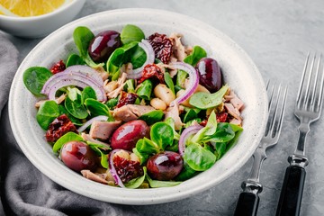 salad with white beans, tuna, olives, red onions and dried tomatoes with green lettuce leaves