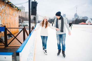 Love couple, man learn woman to skate on the rink