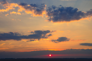 Beautiful colorful sunset sky background with the light of sun behind.Blue and purple clouds. 