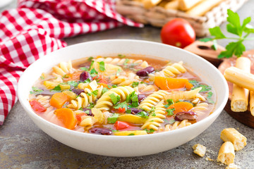 Minestrone soup. Vegetable soup with fresh tomato, celery, carrot, zucchini, onion, pepper, beans and pasta. Dish of italian cuisine.