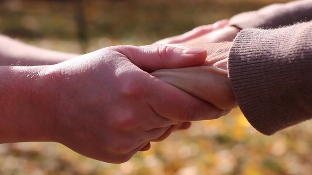 Hands of senior man touching young hand, helping and care for elderly concept